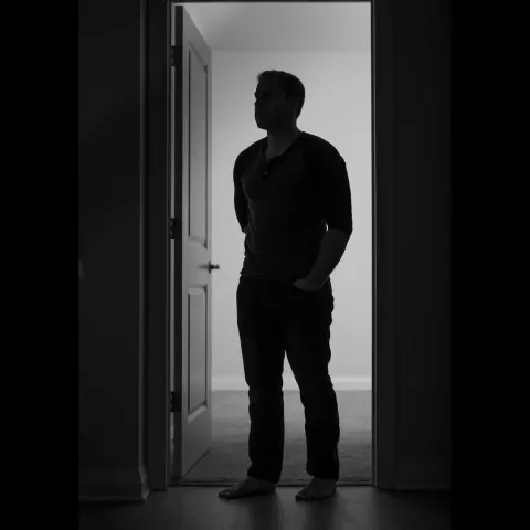 Silhouette of a man standing in a lit doorway