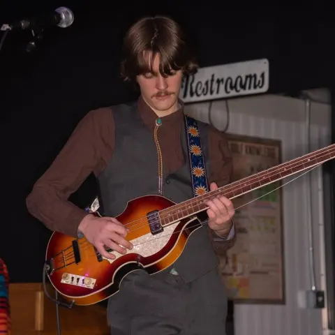 Bassist playing a violin bass on a small stage