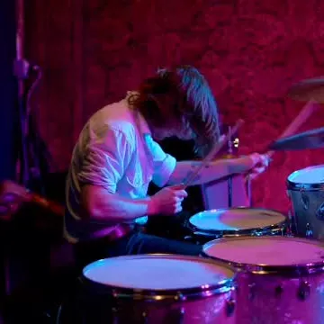 Drummer playing under red and purple stage lights