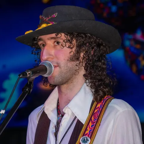Singer in a wide-brimmed hat at a microphone